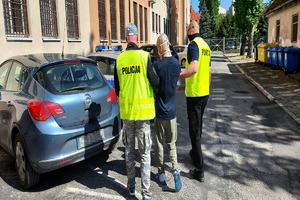 Policjanci prowadzą do auta zatrzymanego