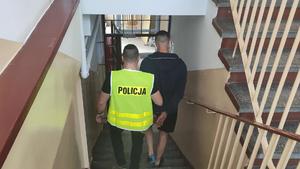 Policjant schodzi po schodach z zatrzymanym włamywaczem