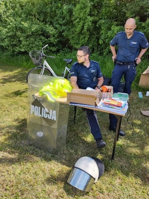 policjanci stoją przy biurku ustawionym w parku