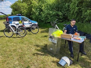 policjanci stoją przy biurku ustawionym w parku