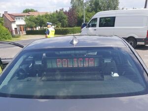 Nieoznakowany radiowóz za nim stoi policjant