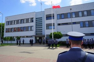 widok na budynek, przed którym stoją policjanci i Komendant