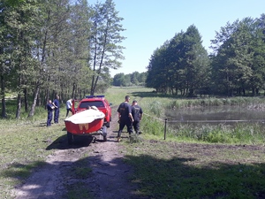 Policjanci i strażacy nad brzegiem akwenu