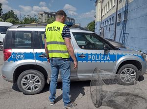 Policjant stoi przy radiowozie, a obok leżą zabezpieczone sieci