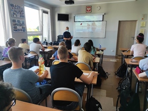 Policjantka przemawia do siedzących dzieci w ławkach