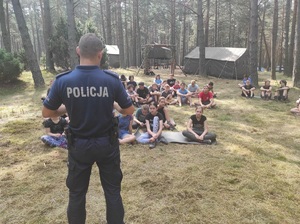 Policjant na rozmowie z obozowiczami w lesie.