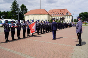 Komendant Wojewódzki oddaje honor przed pocztem sztandarowym. Obok stoją policjanci w szeregu