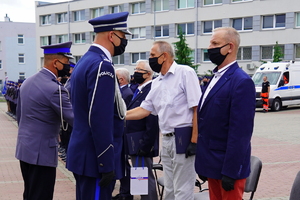 Komendant Wojewódzki gratuluje i przekazuje teczkę starszemu mężczyźnie