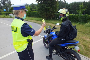 policjantka przekazuje kierowcy motocykla kamizelkę odblaskową