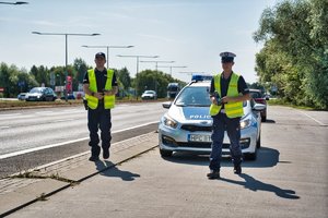 Dwóch policjantów stoi przed radiowozem