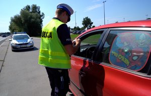 Policjant bierze od kierowcy dokumenty do kontroli