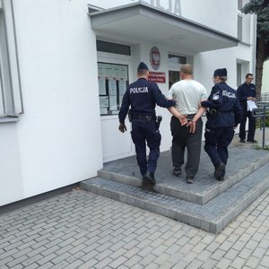 Policjanci wchodzą z podejrzanym do posterunku