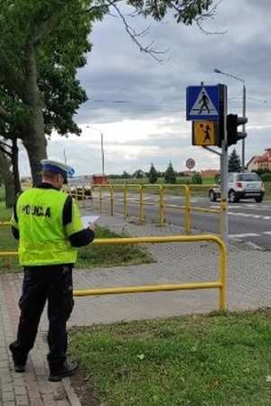 Policjant sprawdza oznakowanie przy szkole