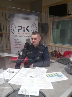 Policjant siedzi przy stole w radiu PiK