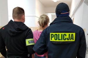 Policjanci stoją obok zatrzymanej