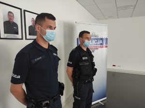 Dwóch policjantów stoi przy ścianie