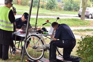 Policjant kuca przy rowerze i znakuje ramę