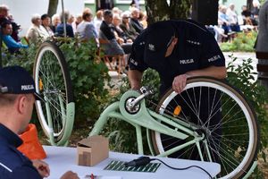 Policjant kuca przy rowerze i znakuje ramę