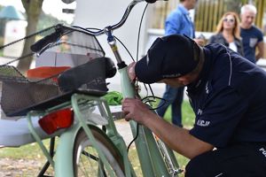 Policjant kuca przy rowerze i znakuje ramę