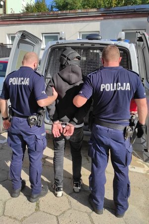 Policjanci prowadzązatrzymanego do radiowozu