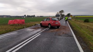 Nissan micra stoi na środku DK 25 obok stoi technik policyjny, a w polu stoi parawan straży