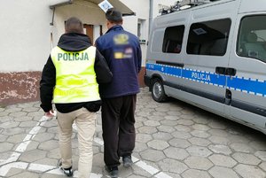 Policjant prowadzi do komendy drugiego z zatrzymanych