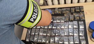 Policjant rozkłada zabezpieczone porcje narkotyków