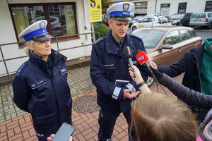 dwoje policjantów rozmawiają z dziennikarzami