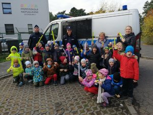 policjanci i dzieci pozują do zdjęcia na tle radowozu