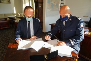 Komendant Wojewódzki Policji w Bydgoszczy i Regionalny Dyrektor Ochrony Środowiska w Bydgoszczy podpisują przy stole porozumienie