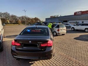 Policyjne bmw stoi obok auta, które kontrolują policjanci