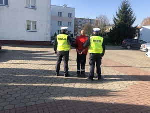 Policjanci prowadzą zatrzymanego kierowcę