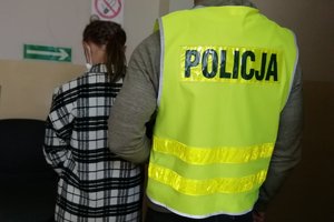 Policjant prowadzi zatrzymaną kobietę