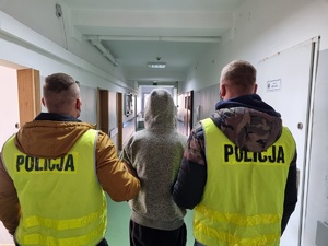 Policjanci prowadzą zatrzymanego mężczyznę