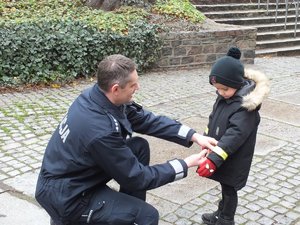 Policjant daje odblaskową opaskę maluchowi