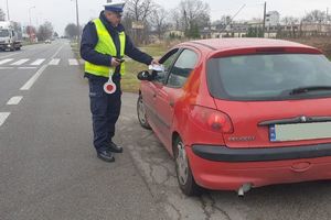 Policjant RD wręcza kierowcy peugeota ulotkę podczas kontroli