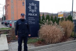 Policjant stojący przed banerem komendy.