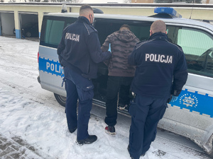 Policjanci prowadzą zatrzymanego mężczyznę