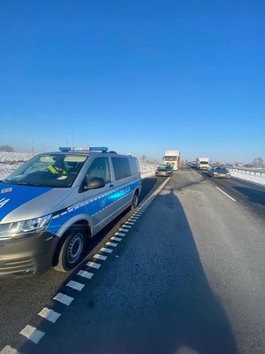 Radiowóz stoi na poboczu, a za nim osobowe audi i ciężarówka