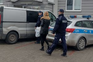 Policjanci prowadza zatrzymaną do radiowozu