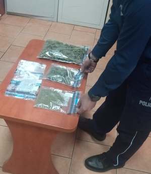 Policjant stoi przy stole z narkotykami