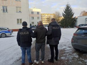 Policjanci prowadzą zatrzymanego mężczyznę