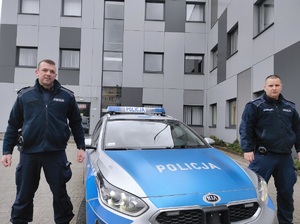 Dwóch policjantów stoi przy radiowozie