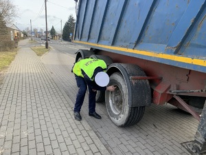 Policjant sprawdza koło ciężarówki.