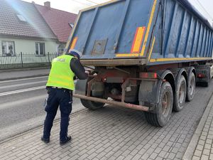 Policjant sprawdza tył auta ciężarowego.