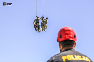 Funkcjonariusze Policji na dużej wysokości zwisający na linach.