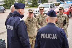 Trzech żołnierzy patrzy w kierunku komendanta policji
