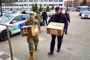 Komendant wraz z żołnierzem niosą kartony z datkami