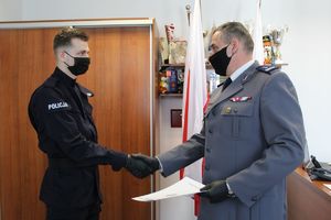 Komendant wręcza rozkaz nowo przyjętemu policjantowi