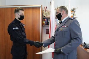 Komendant wręcza rozkaz nowo przyjętemu policjantowi
